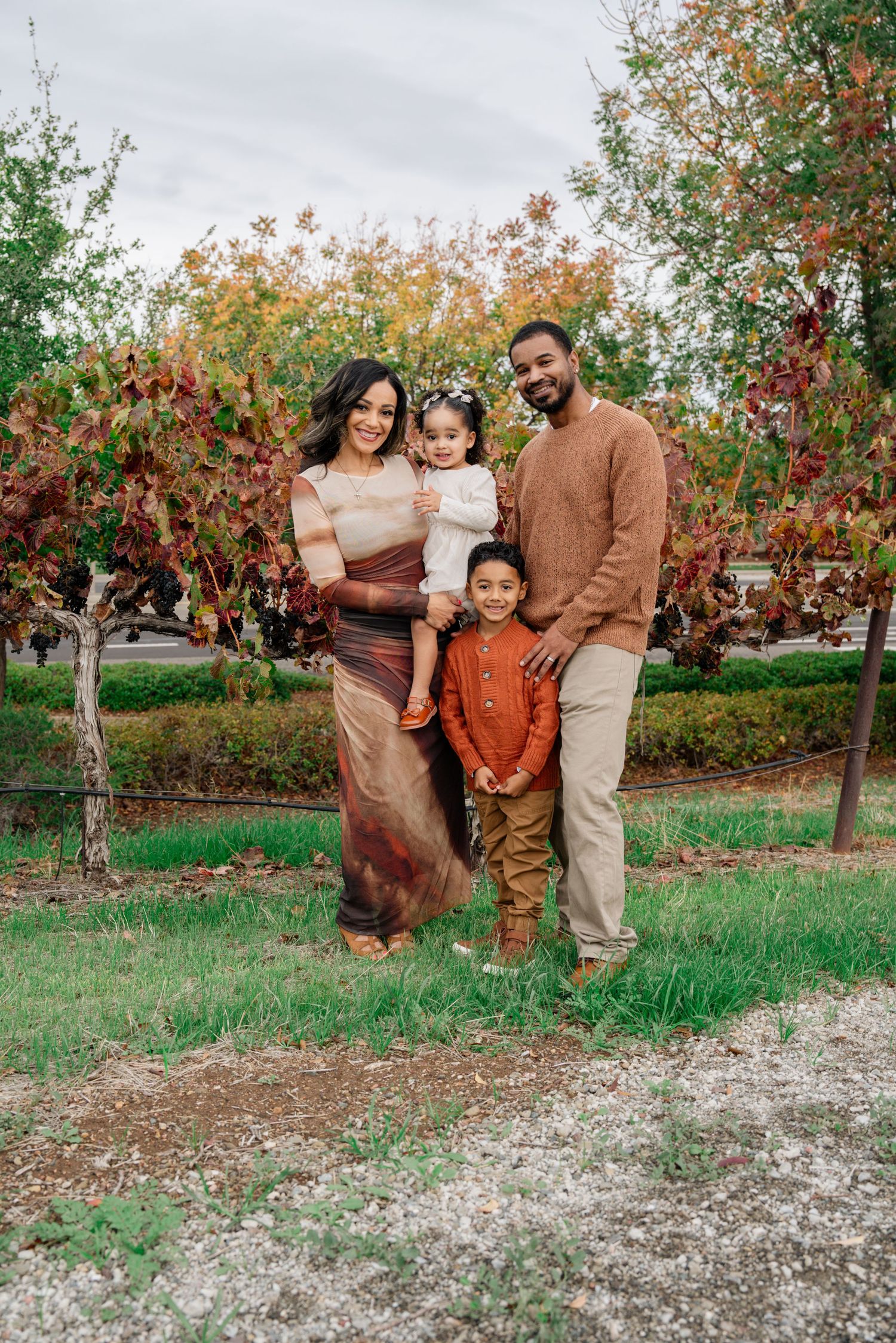 Family portrait session in an orchard with fall colors and trees.
