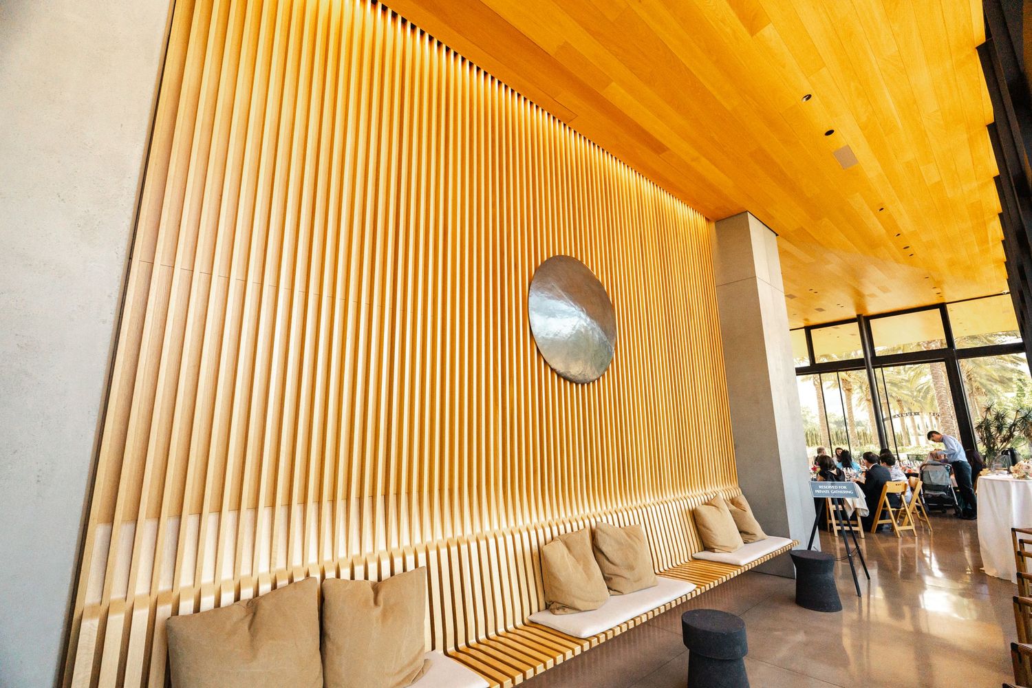 Modern interior featuring wooden slat wall design with circular window and built-in seating.