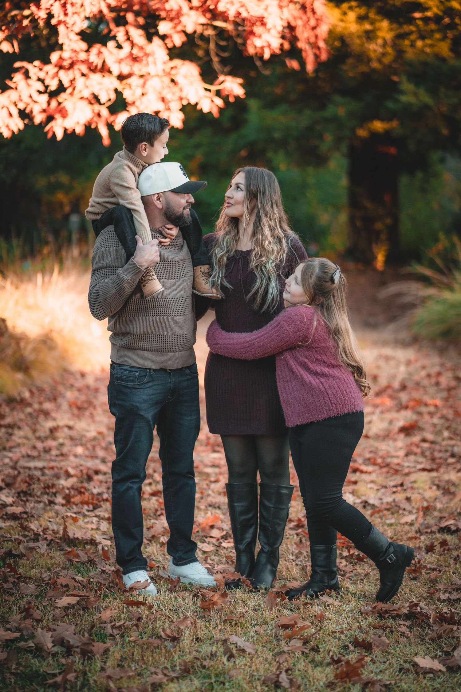 A family shares a joyful moment together in a fall forest setting with golden leaves.