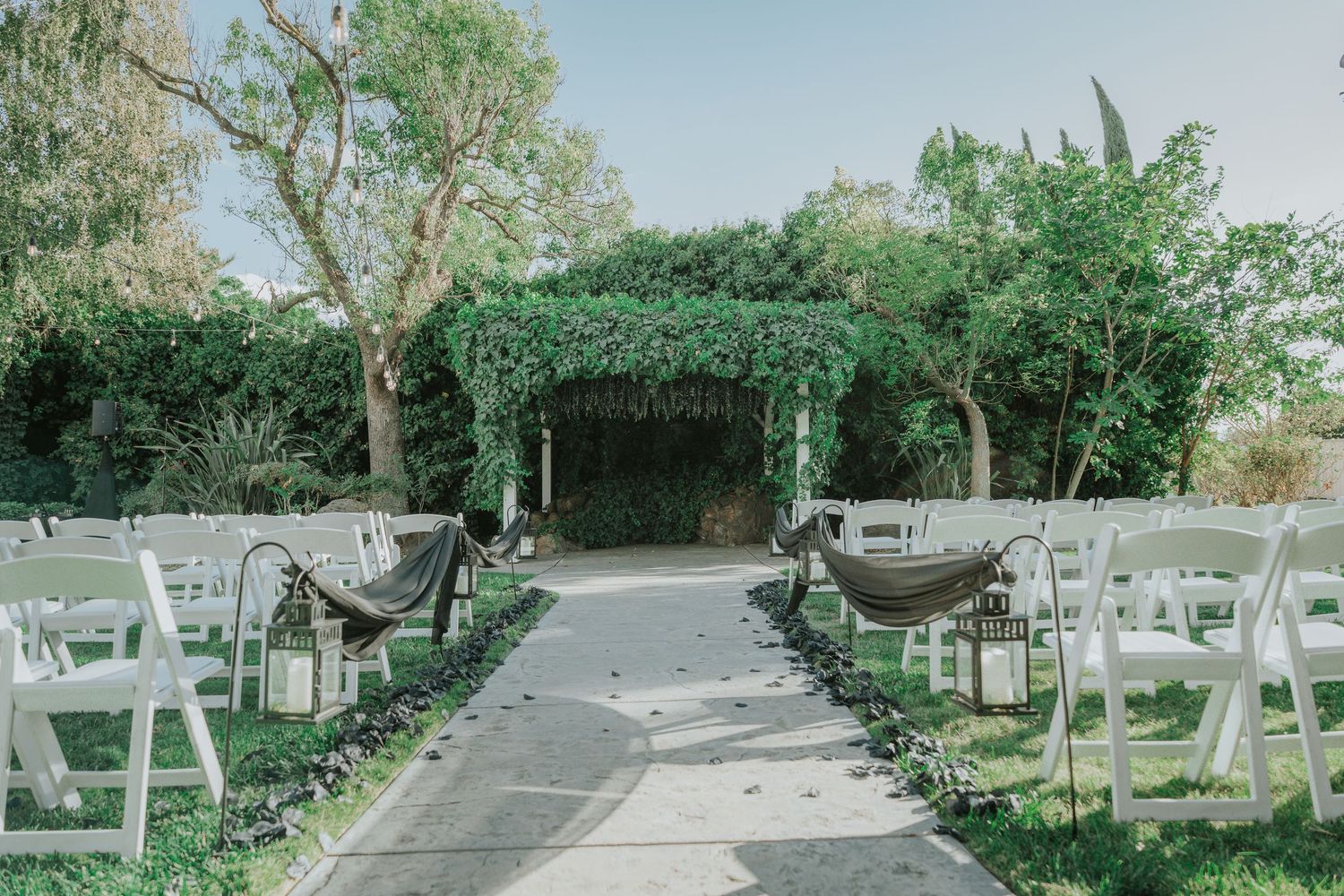 Pathway through landscaped garden with white chairs set up for event at La Grande Estates
