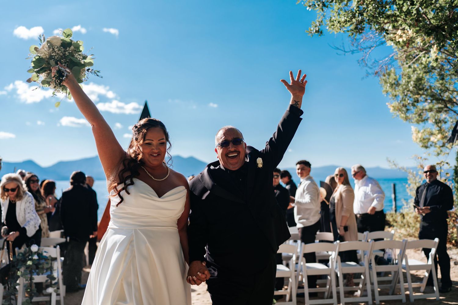 Wedding ceremony in progress with guests seated under blue skies and mountain backdrop.