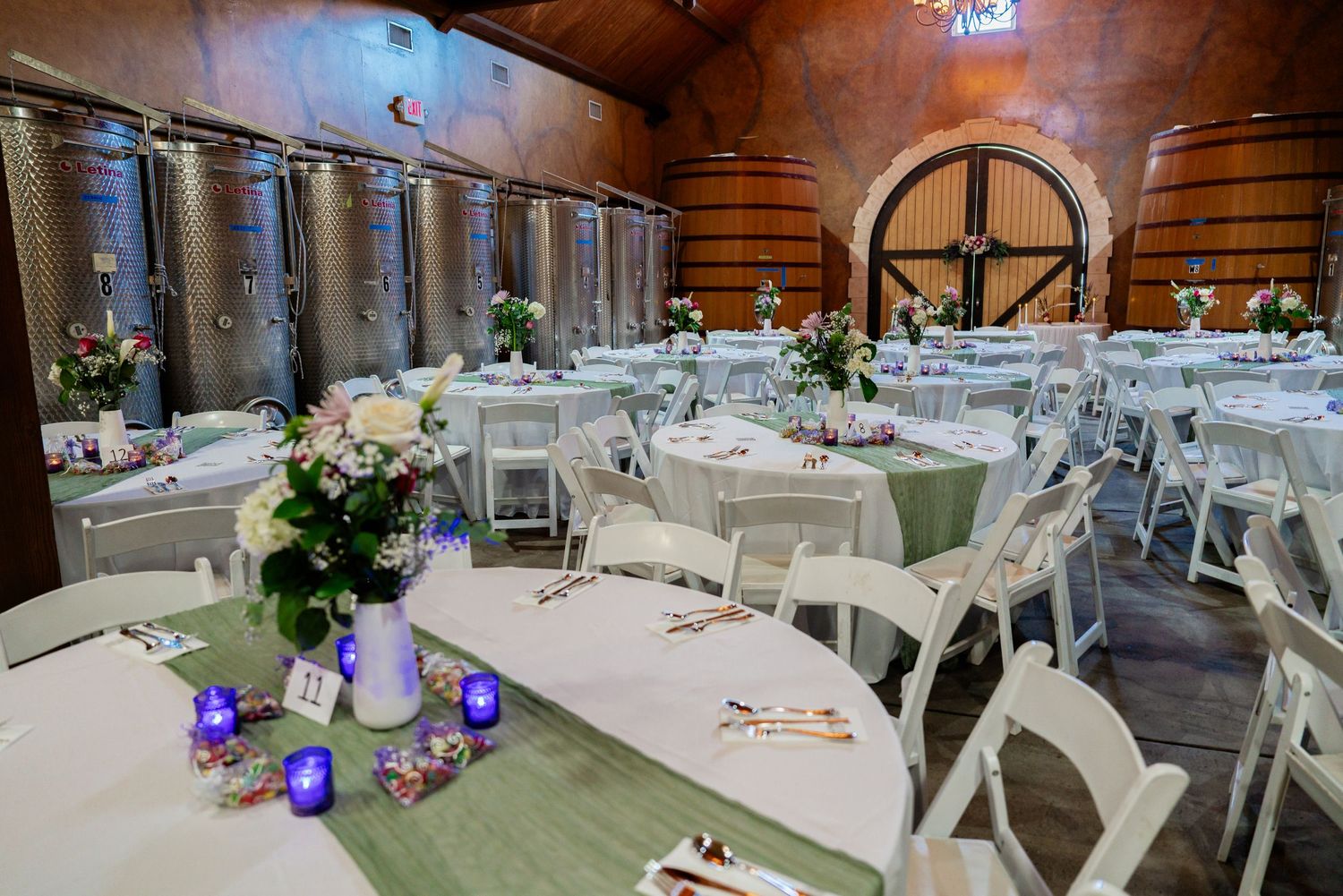 Wedding reception hall decorated with purple uplighting and elegant table settings.