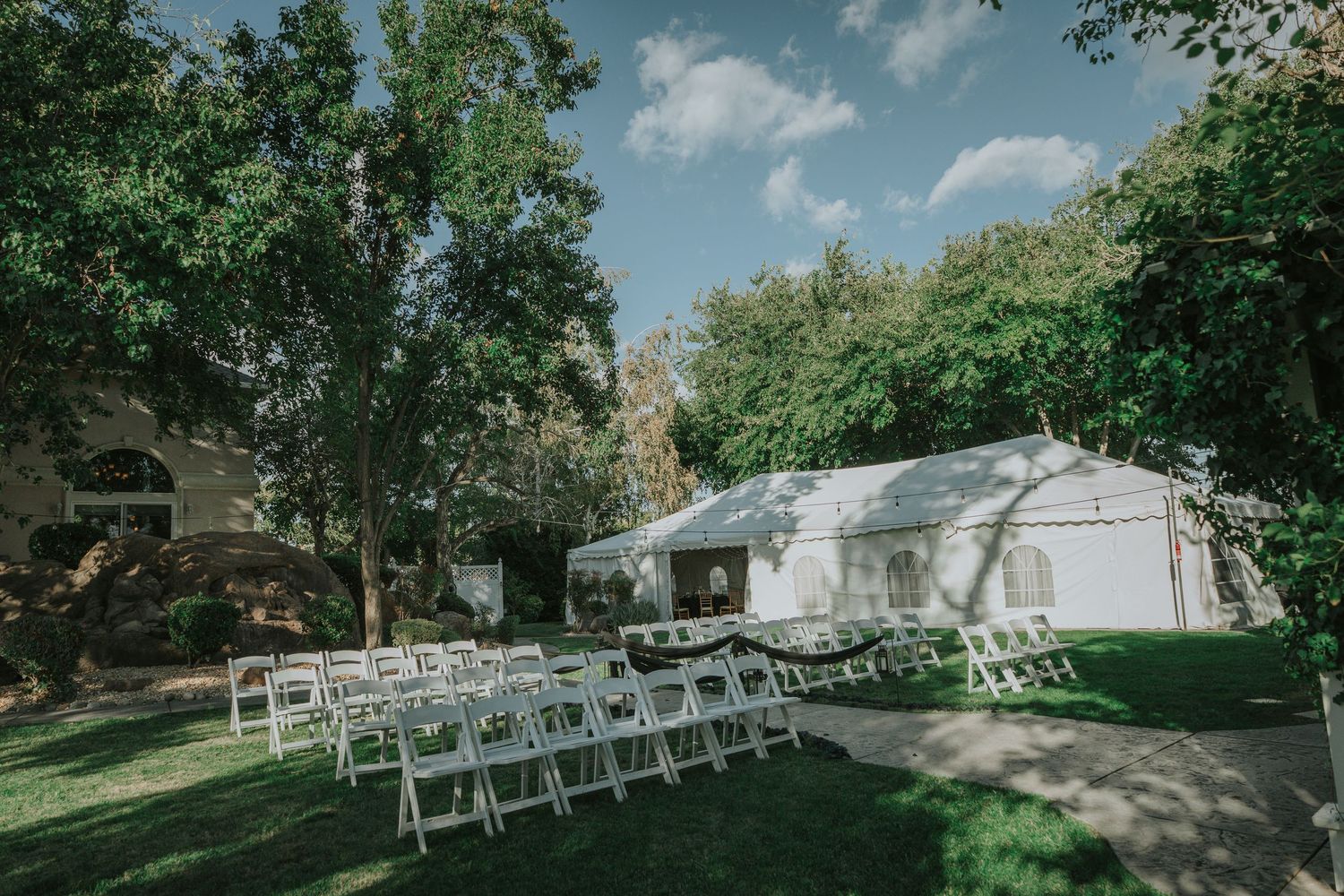 Garden wedding venue with chairs arranged under shady trees at La Grande Estates