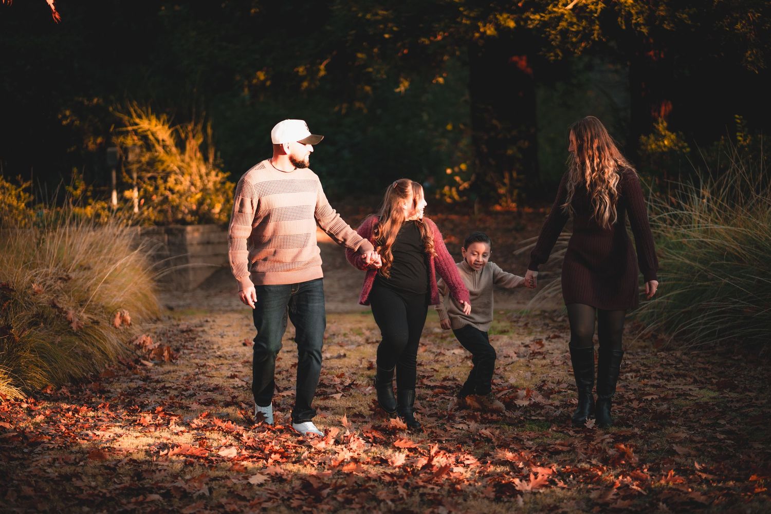 Silhouettes of people walking together against a sunset backdrop with fallen autumn leaves.