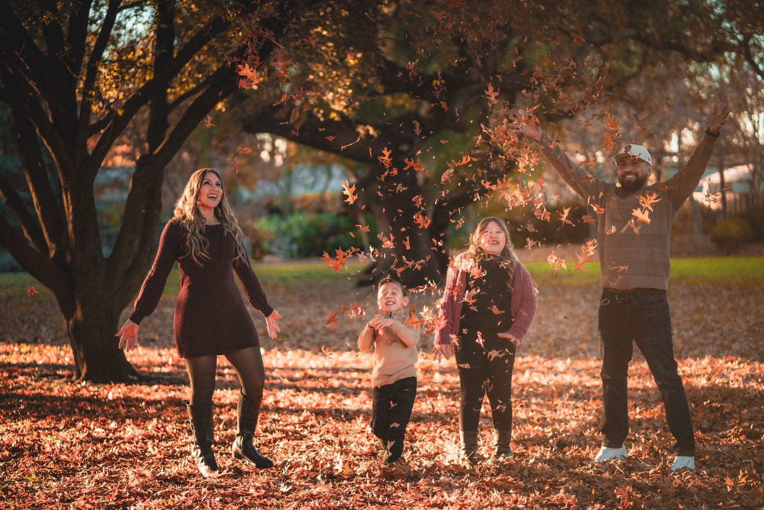 People walking and playing among fallen leaves in an autumn park setting.