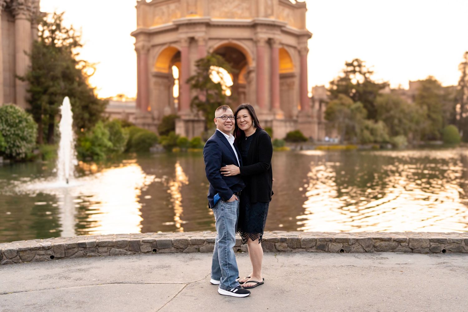 A couple poses near the Palace of Fine Arts in San Francisco during golden hour.