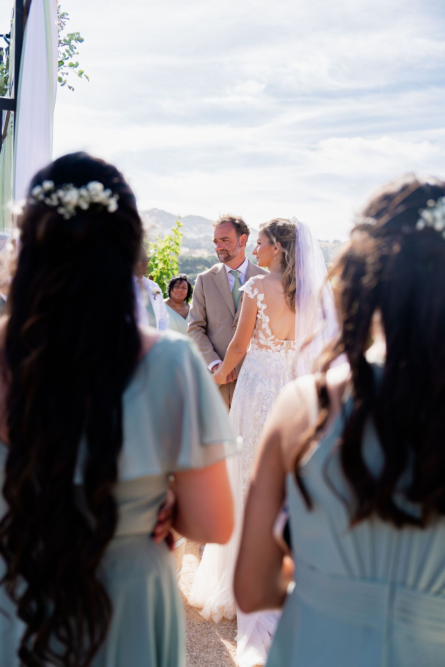 Wedding ceremony attendees in light blue dresses watching the proceedings.