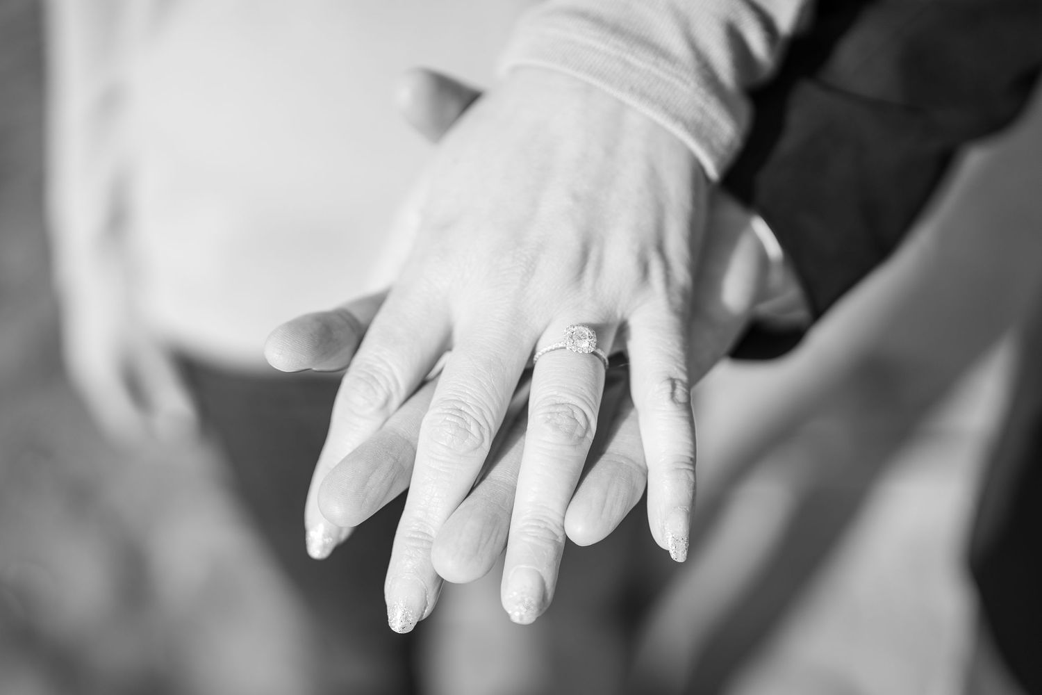 Close up of hands wearing wedding rings against blurred background.