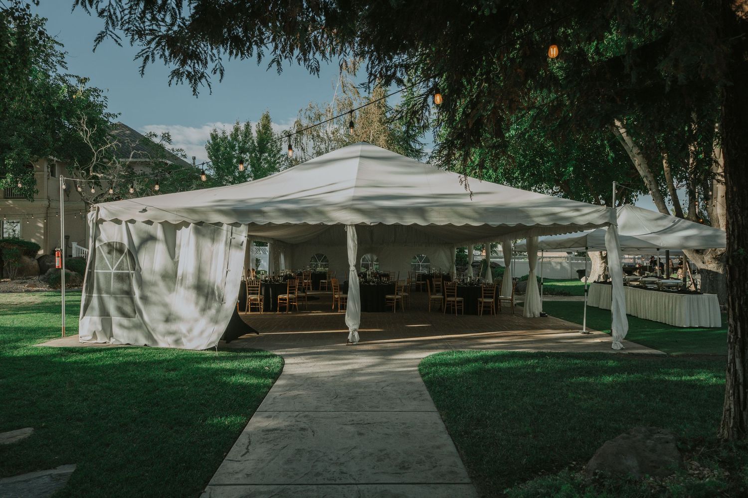 White outdoor wedding tent pavilion set up on a manicured lawn with flowing curtains and pathway at La Grande Estates
