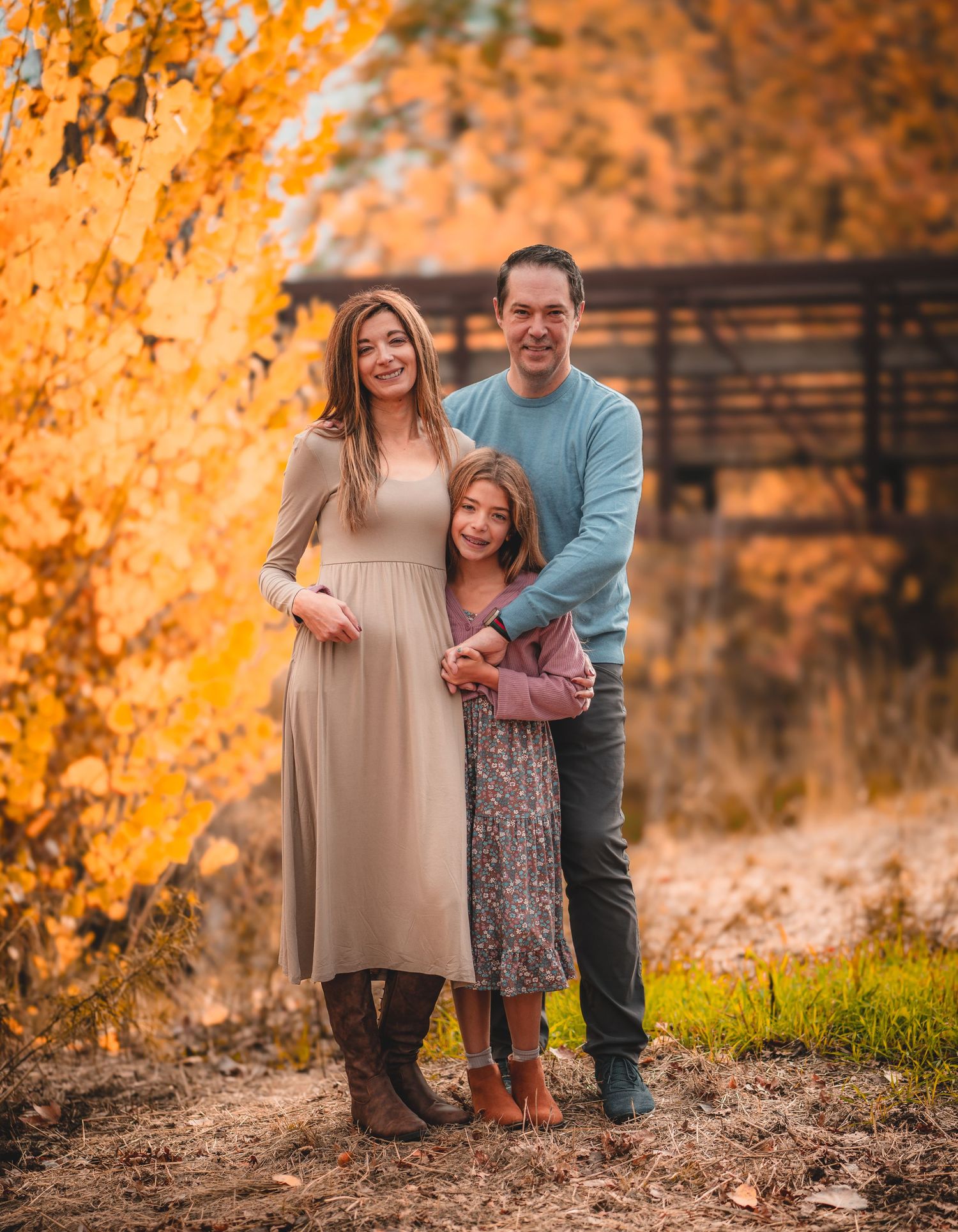 Autumn family photoshoot with warm orange tones and fallen leaves.