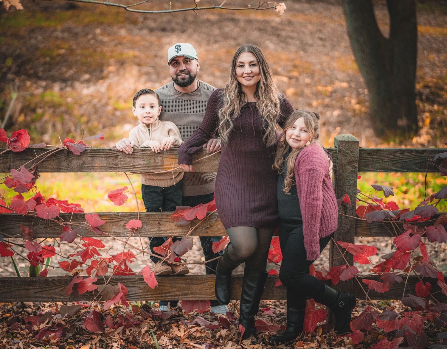 Family photo session in a park with red autumn leaves and natural scenery.