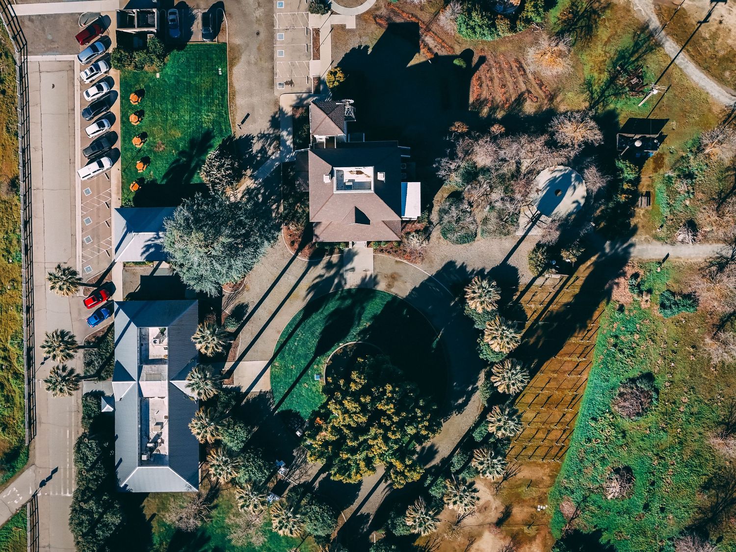 Aerial drone view of a lush residential property with gardens, trees, and a house surrounded by greenery.
