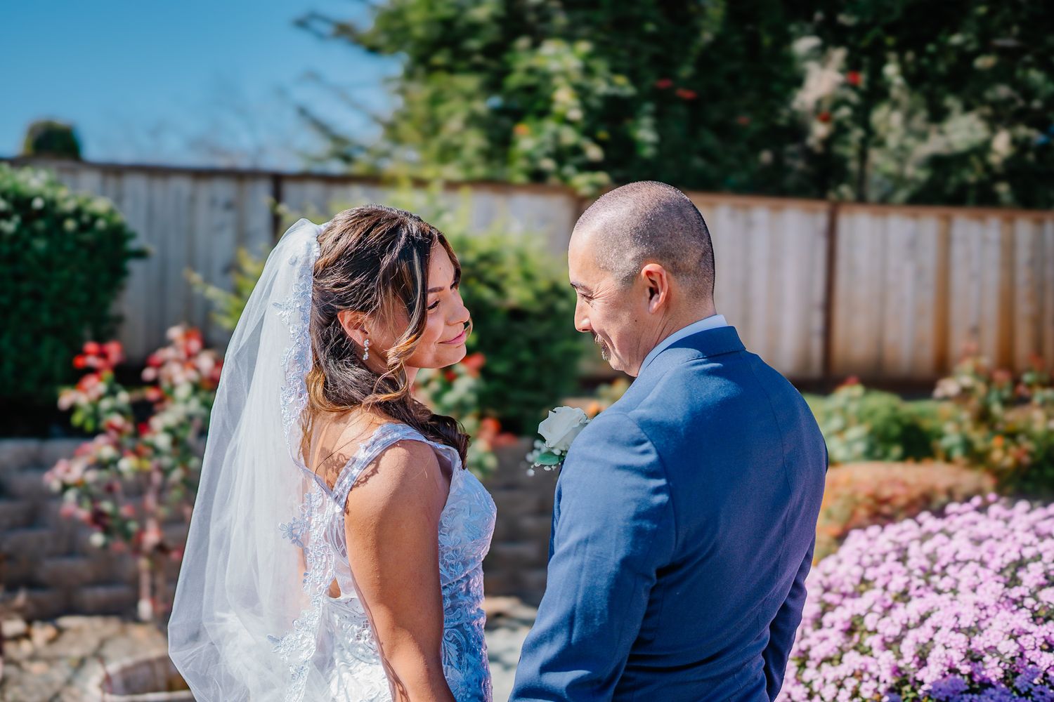 Bride and groom sharing an intimate moment outdoors, surrounded by colorful garden flowers on their wedding day.