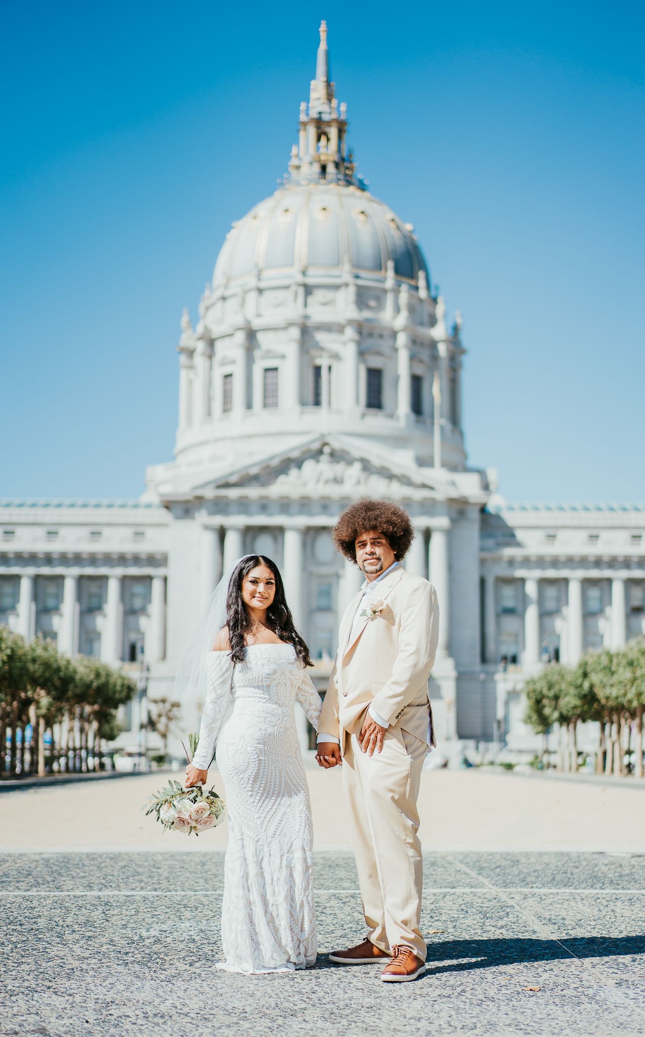 Wedding couple posing in front of San Francisco City Hall's iconic Beaux-Arts architecture.