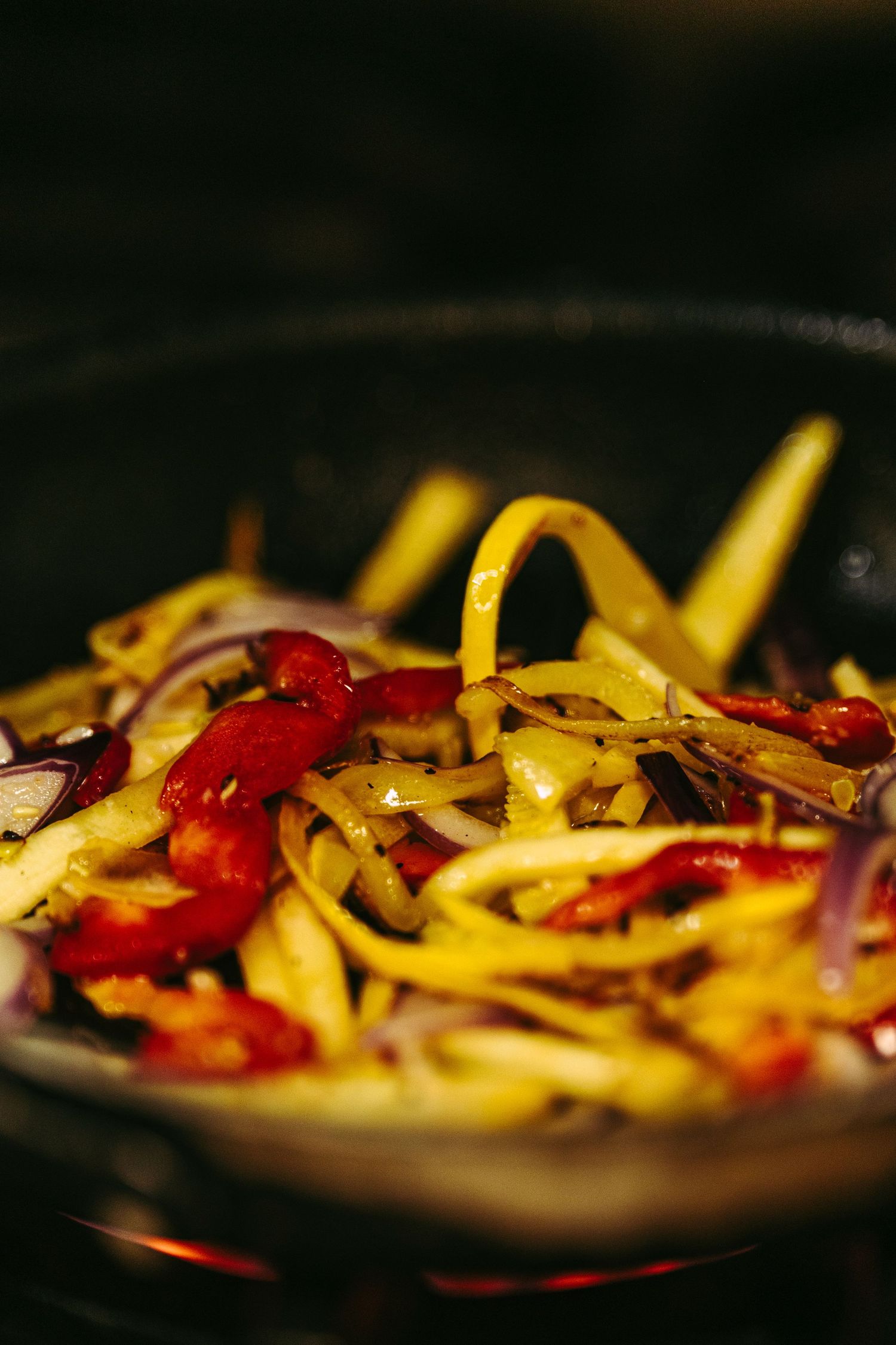 Colorful sautéed vegetables including onions and red peppers cooking in a wok.