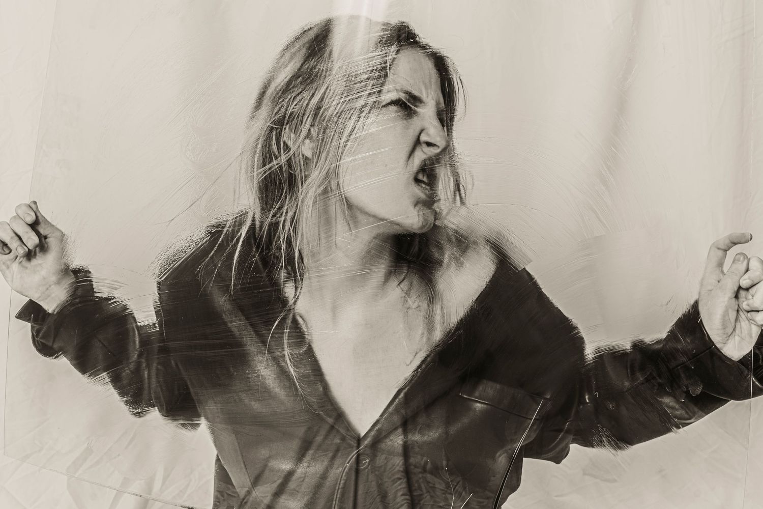 Black and white photo of woman in open jacket with arms outstretched and hair blowing.