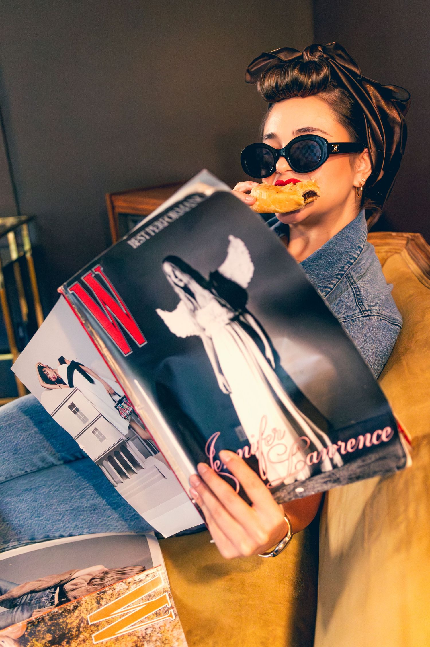 Woman in sunglasses reading W Magazine while eating a waffle, styled in retro pin-up fashion.