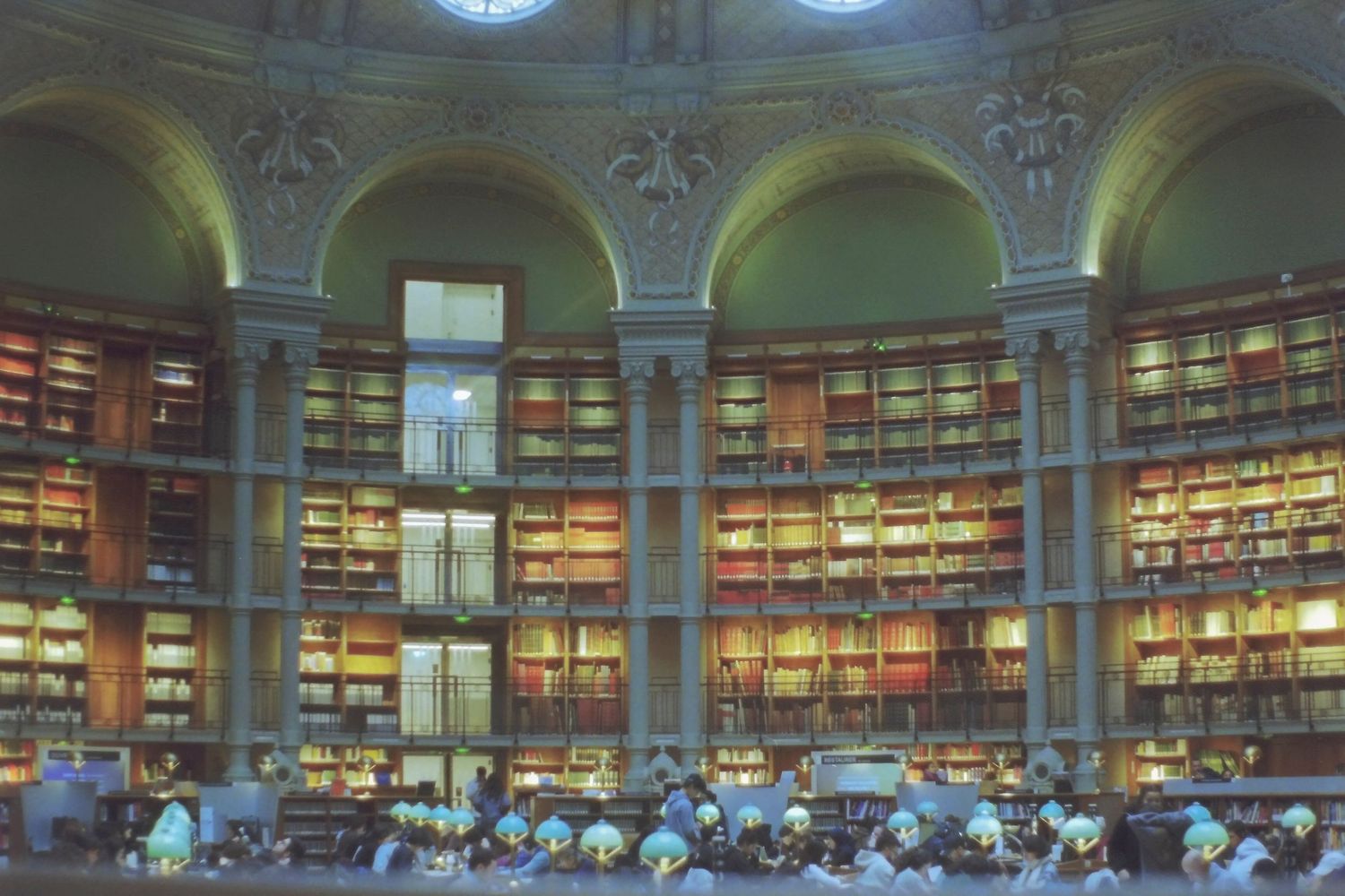Grand circular reading room with towering book-lined walls and arched ceilings in a historic library.