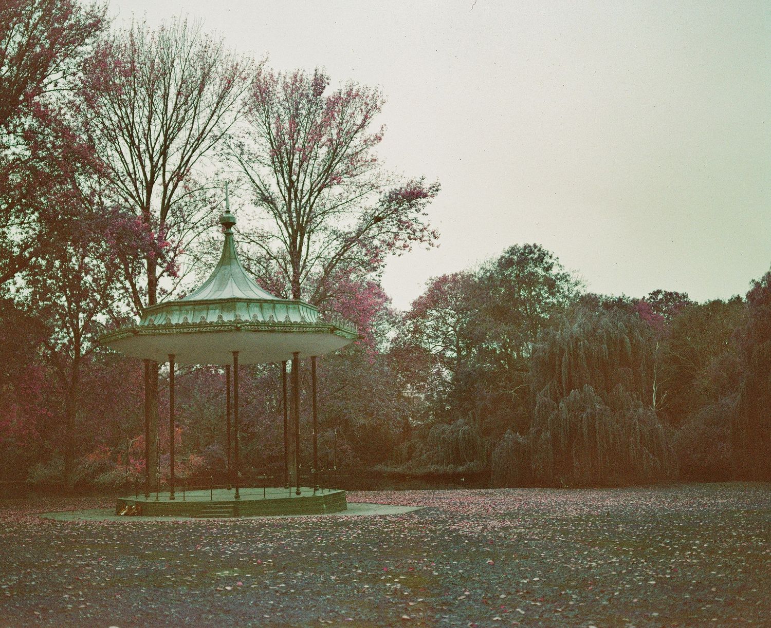 Historic ornate green gazebo bandstand surrounded by autumn trees in a tranquil park setting.