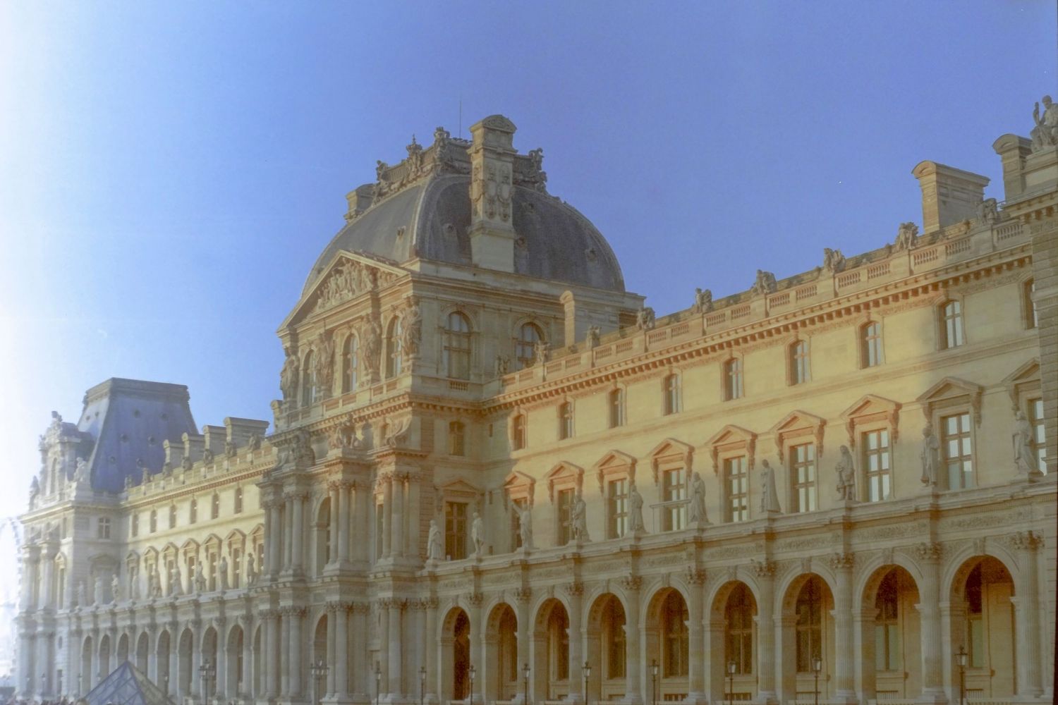 Ornate facade of the Louvre Museum in Paris, France, featuring classical French Renaissance architecture under a clear blue sky.