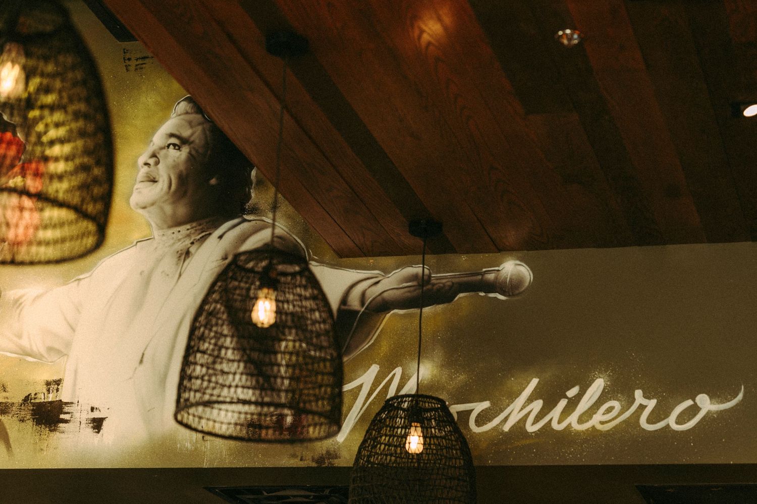 Mochilero restaurant interior with large wall mural and decorative pendant lights.