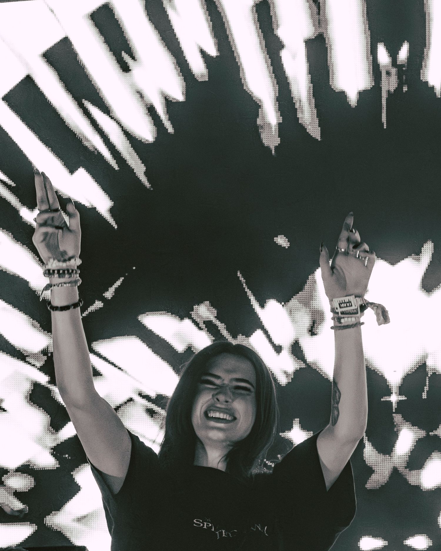 Female DJ raises hands in black and white photo against bold graphic backdrop.