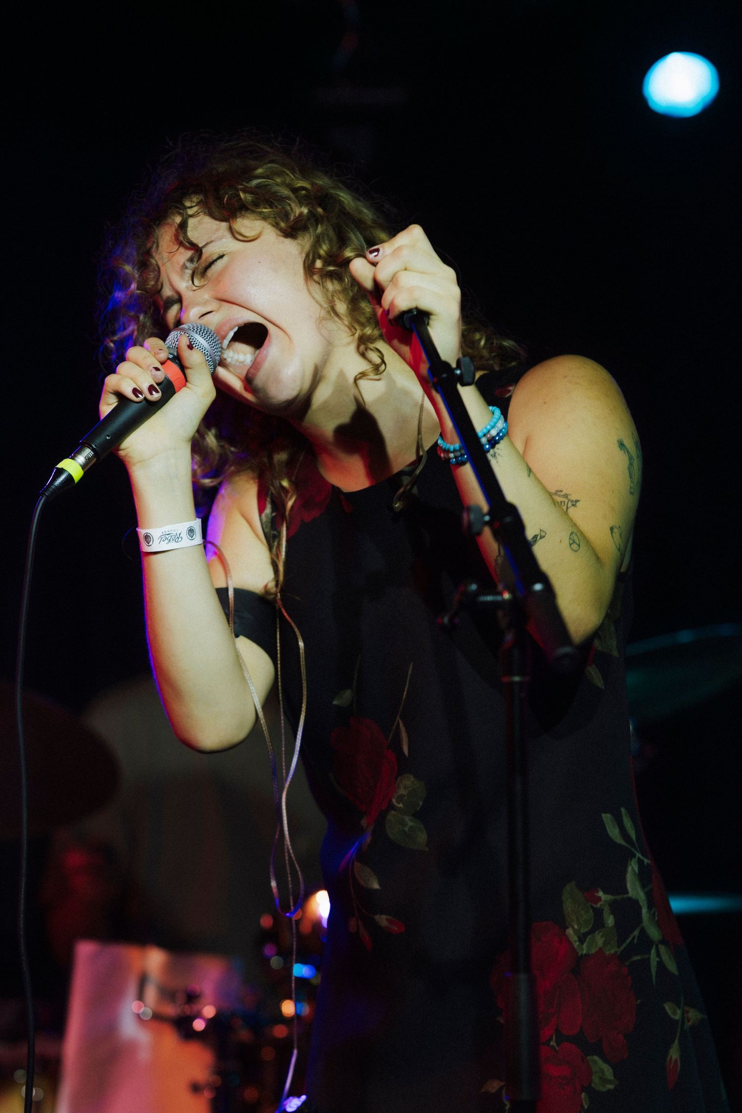 Female vocalist sings intensely into handheld microphone at a dimly lit live concert.