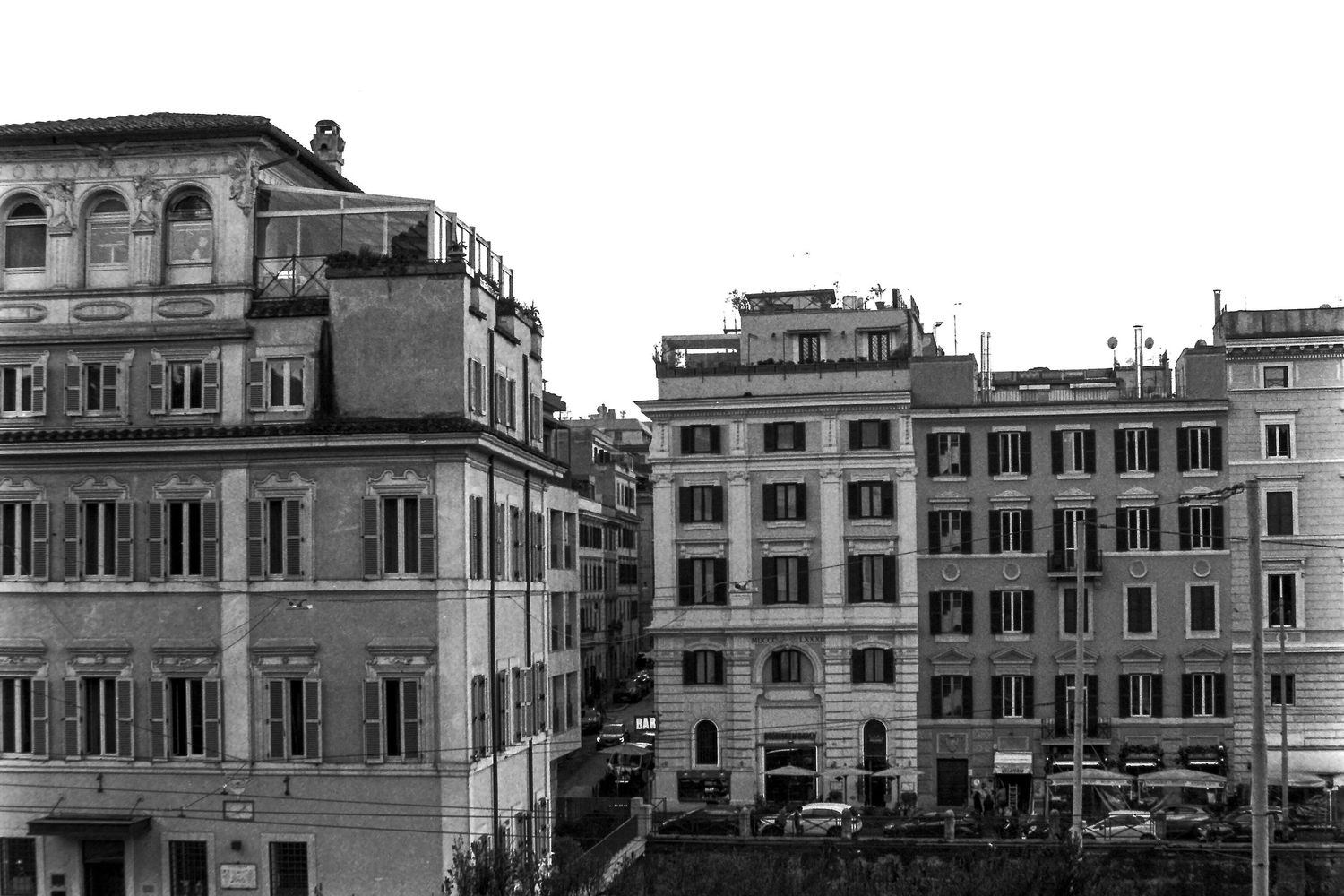 Black and white photo of historic Roman buildings lining a narrow street in Rome, Italy.