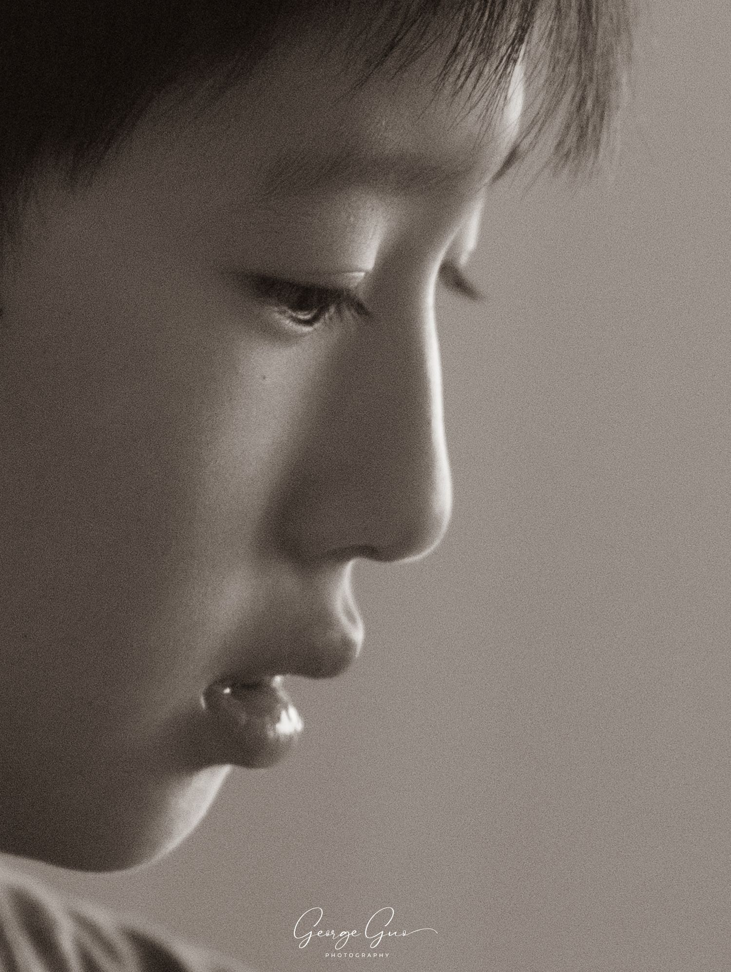 Delicate side-profile close-up of a young boy in black and white, captured in natural light by George Guo Photographer