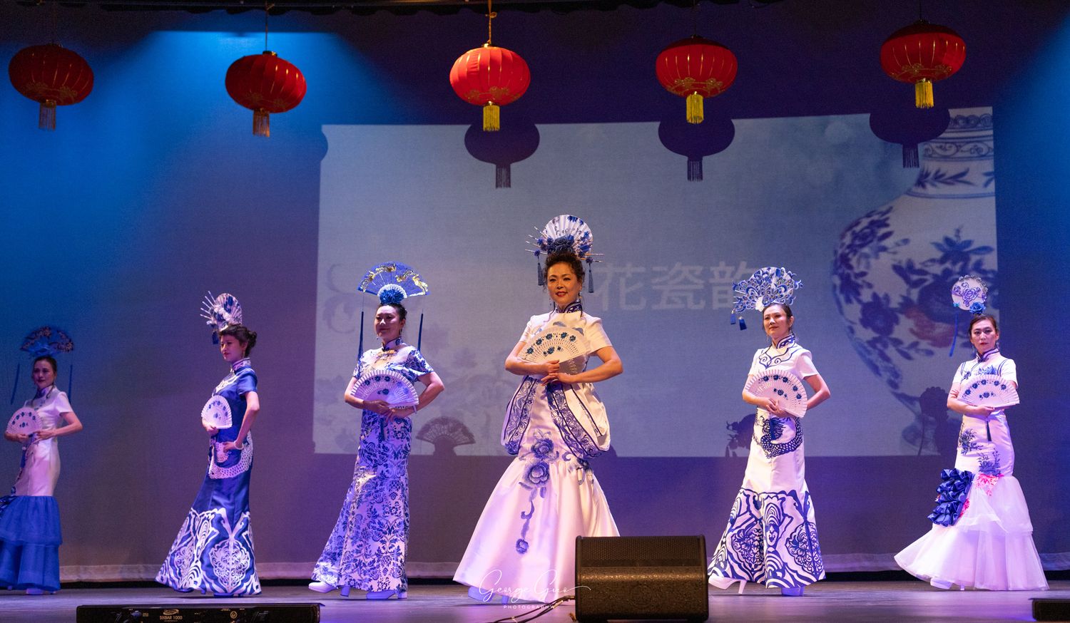 Ladies holding traditional fans and performing a dance in traditional dresses during a show, captured by George Guo Photographer