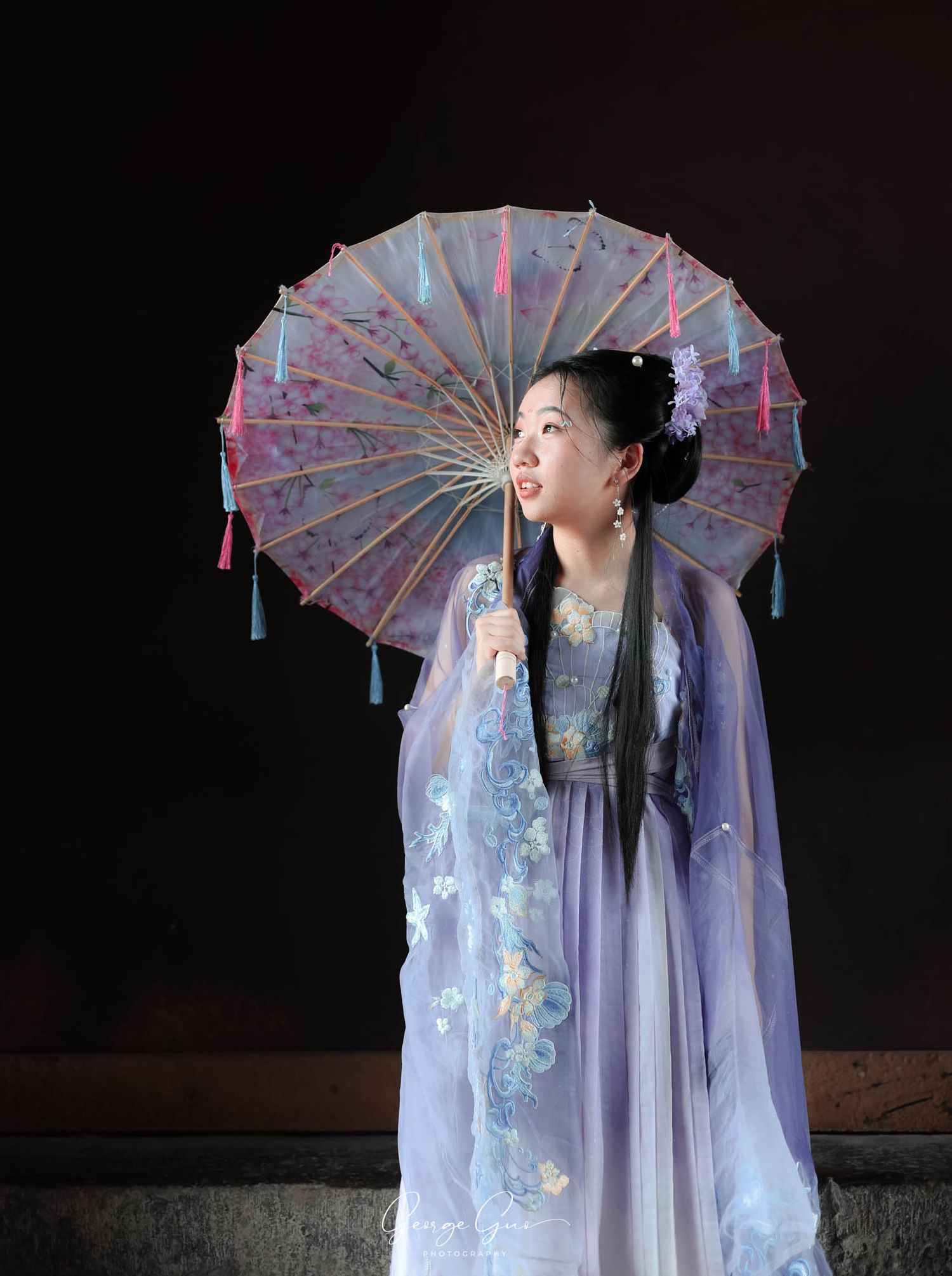 A young girl looking to the side, holding a decorative umbrella, wearing a traditional Chinese dress, captured by George Guo Photography