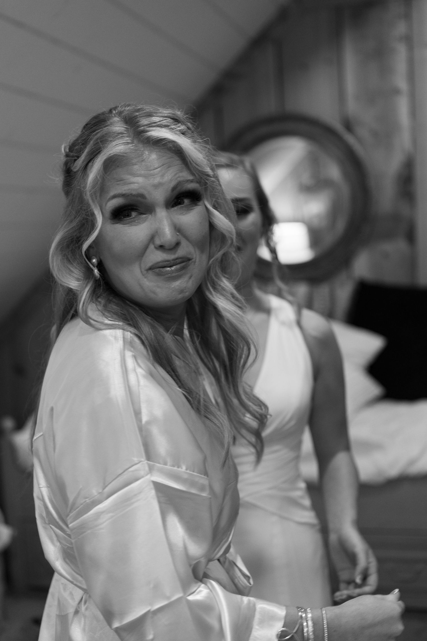 Black and white portrait of woman in white satin robe with curled hair.
