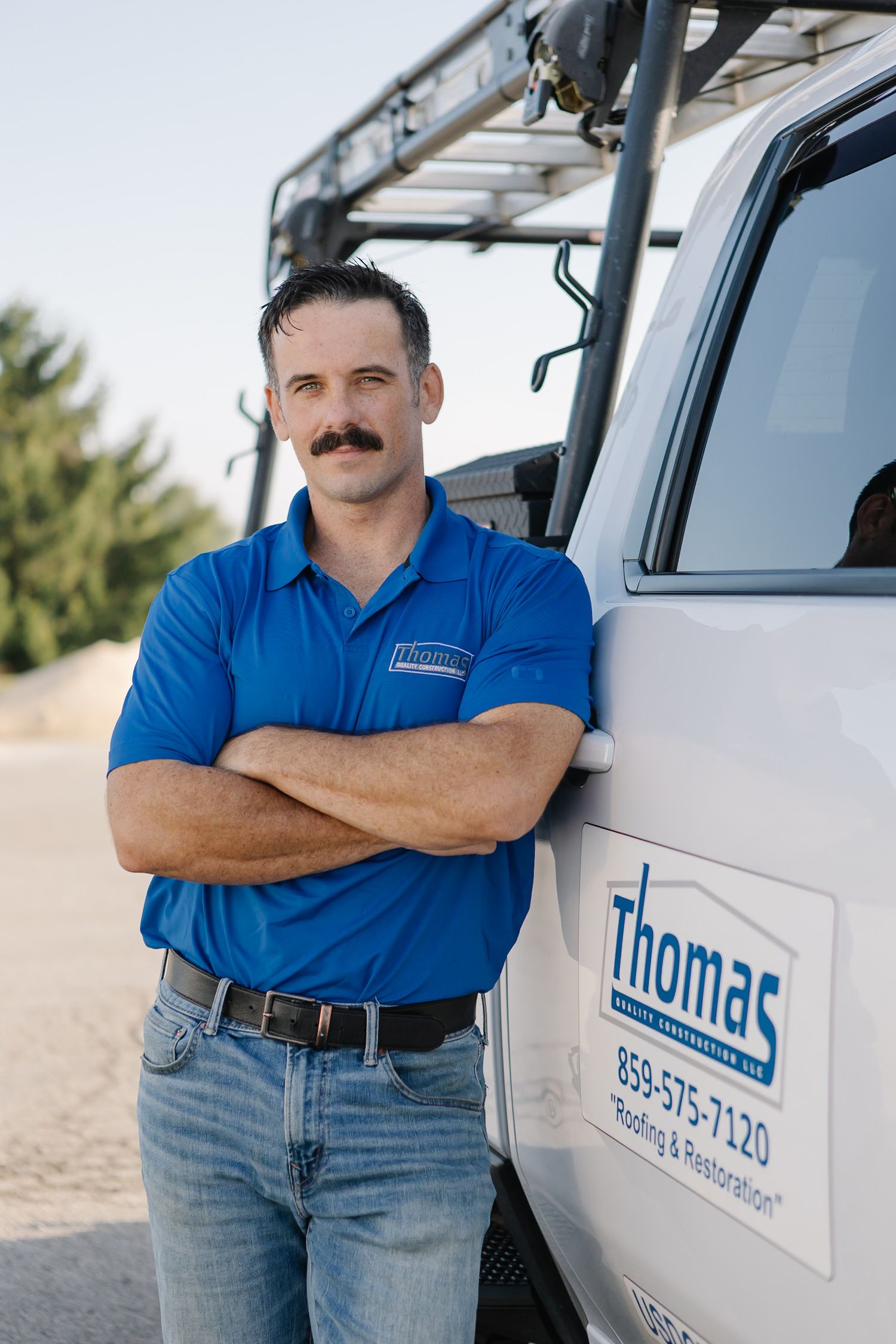 Service technician in blue uniform standing next to company van.
