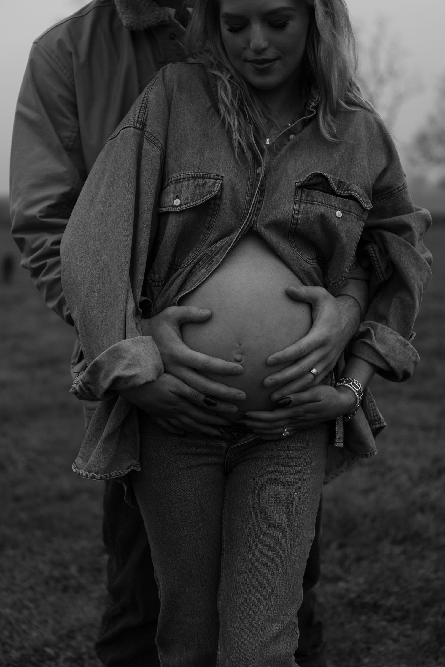Couple embraces in casual denim and western wear on a cloudy day.