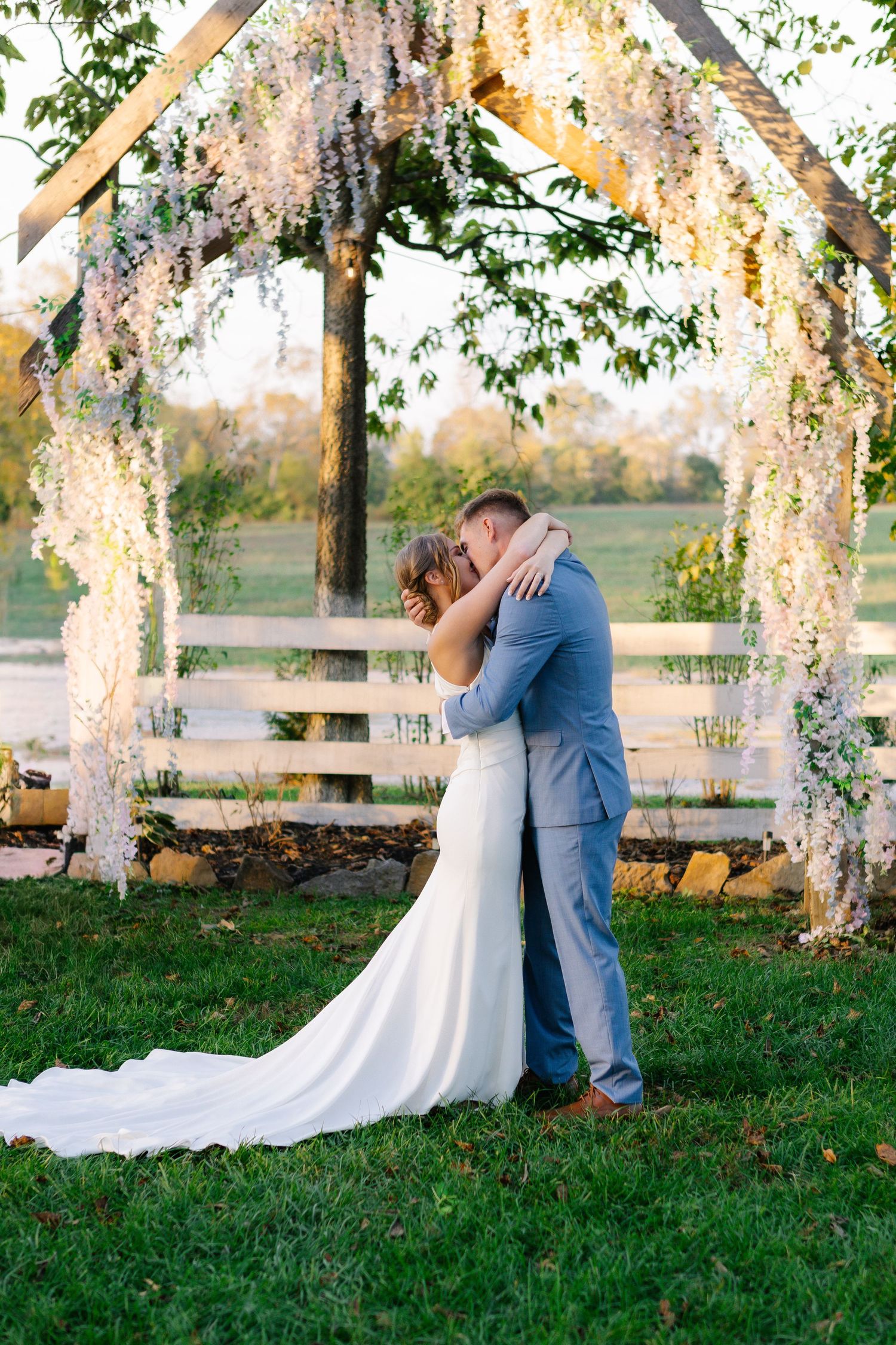 Romantic wedding portraits under flowering trees at golden hour.