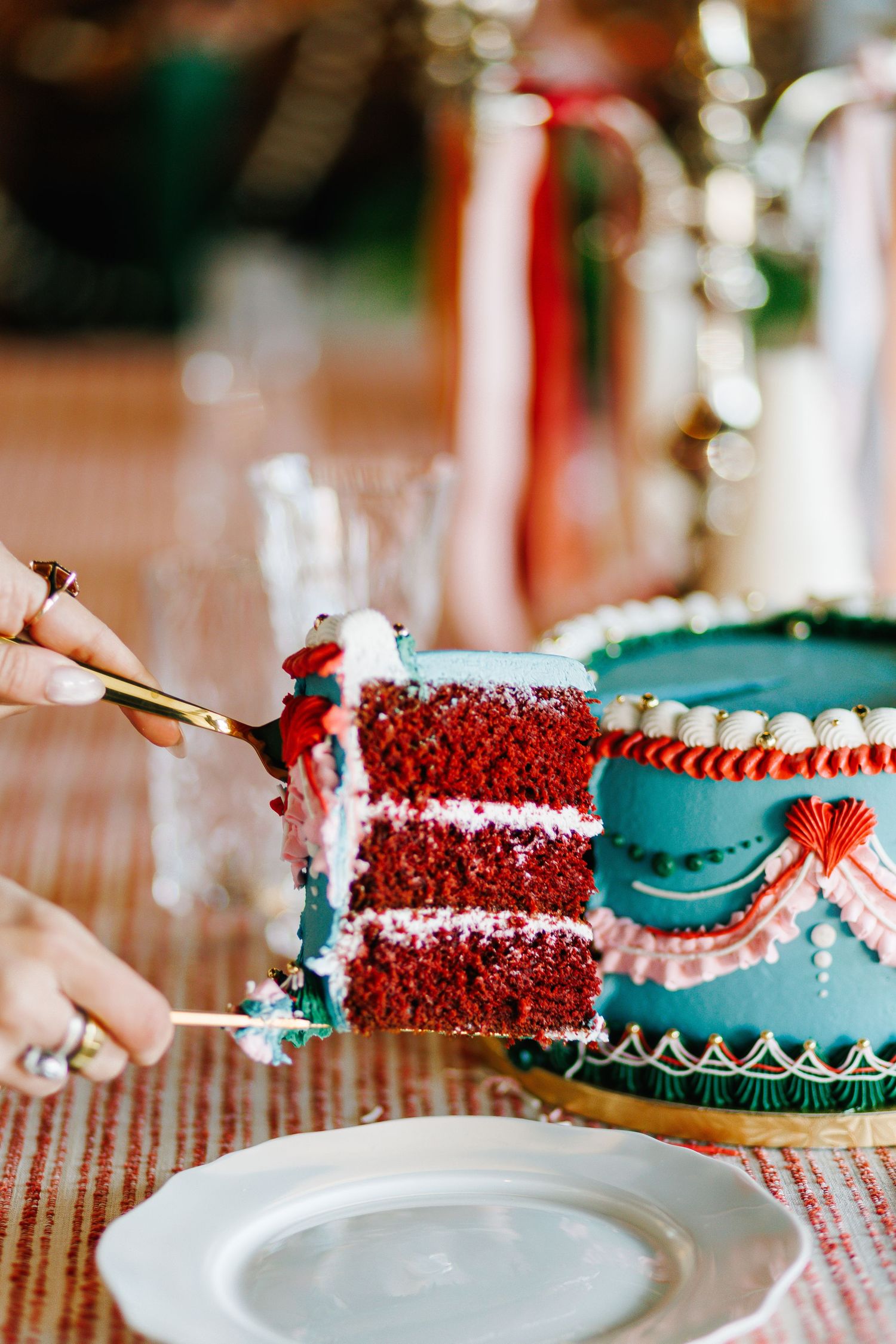 Red velvet cake slices with turquoise frosting displayed on white plates.