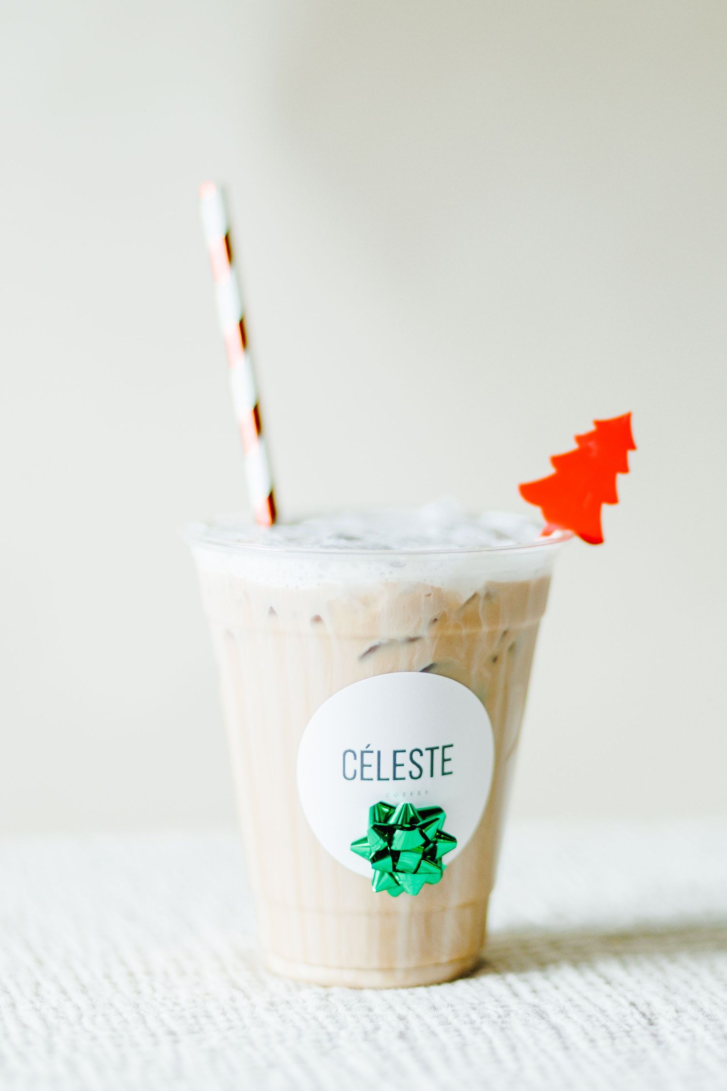 White holiday beverage in a paper cup with festive Christmas decorations.