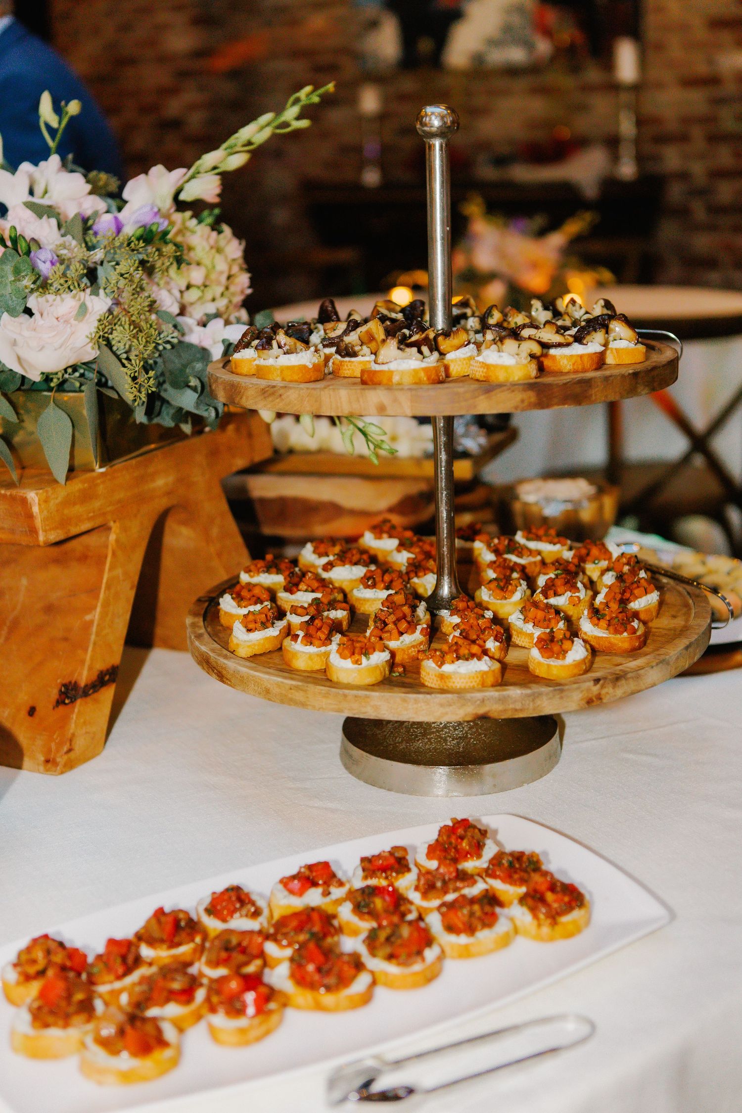 Rows of gourmet bruschetta appetizers arranged on white platters with colorful toppings.