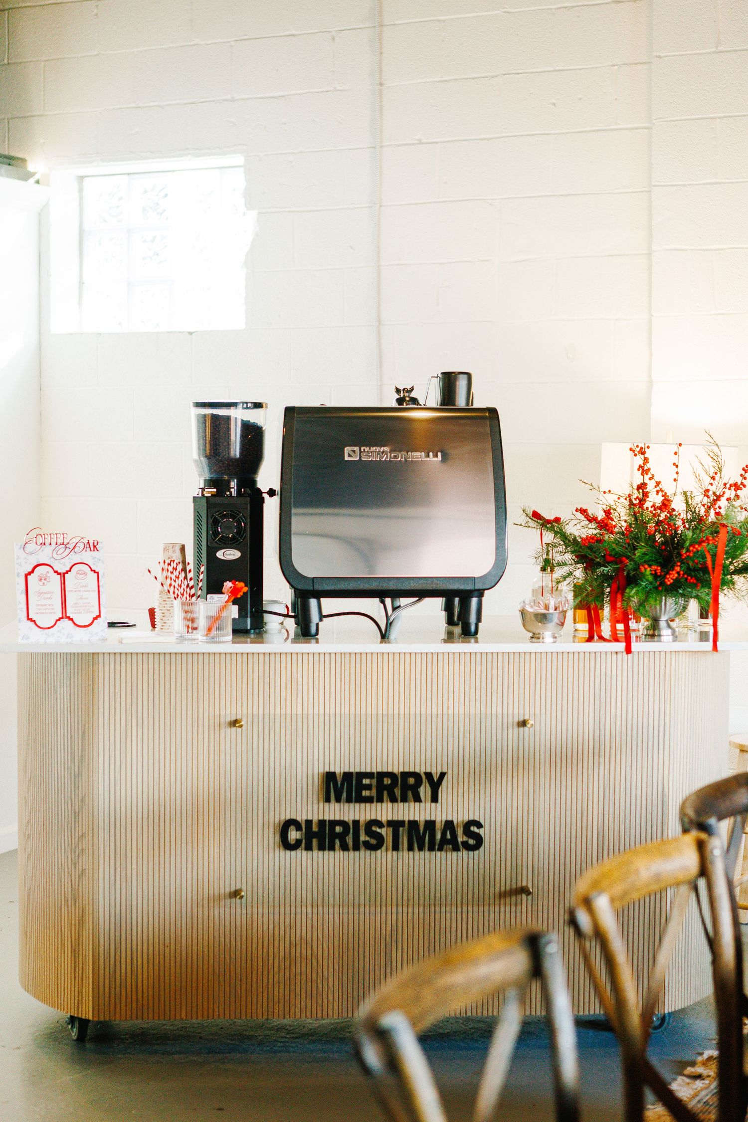 Modern office space decorated with Christmas text and festive red flowers.