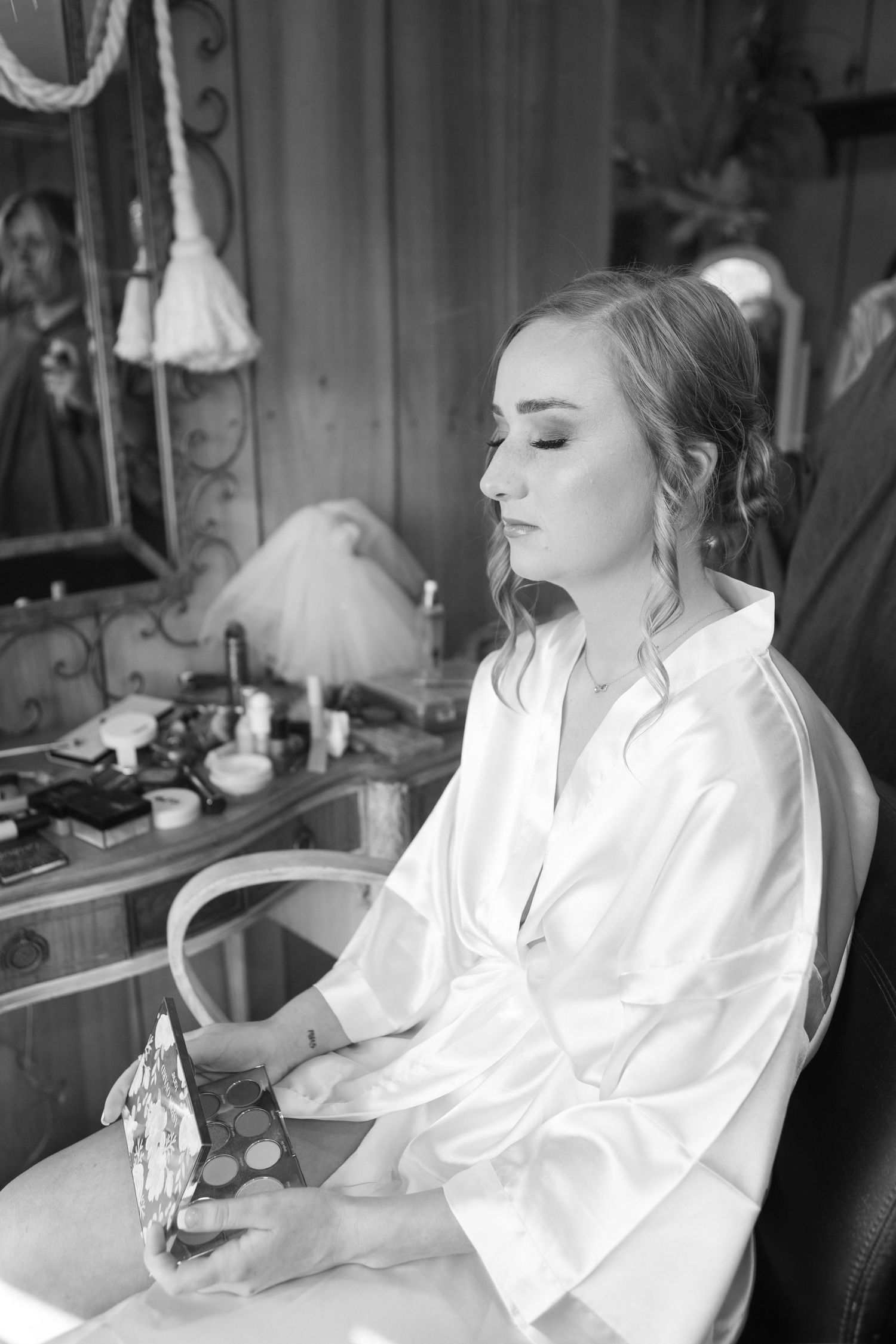 Getting ready scene captured in black and white with soft morning light streaming through windows.