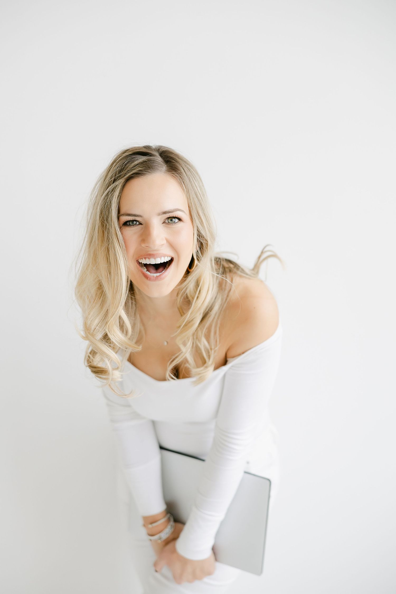 Series of joyful portraits showing woman in white top against white background.