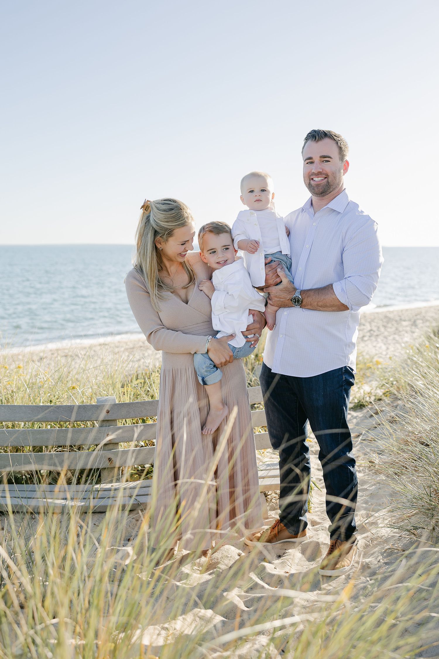 Candid family moments captured in beach grass during golden hour.