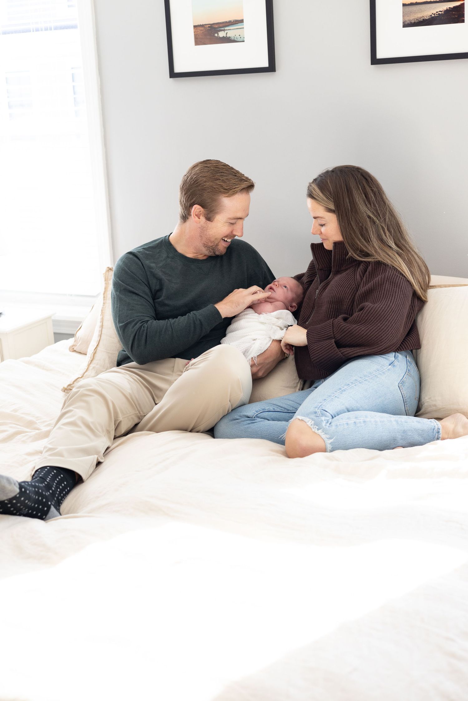 Intimate lifestyle photoshoot of a couple relaxing together on white bedding.