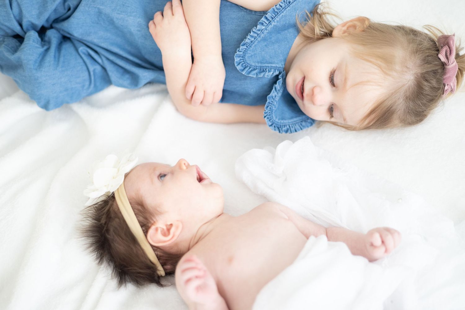 Candid family moments captured on white bedding during lifestyle photoshoot.