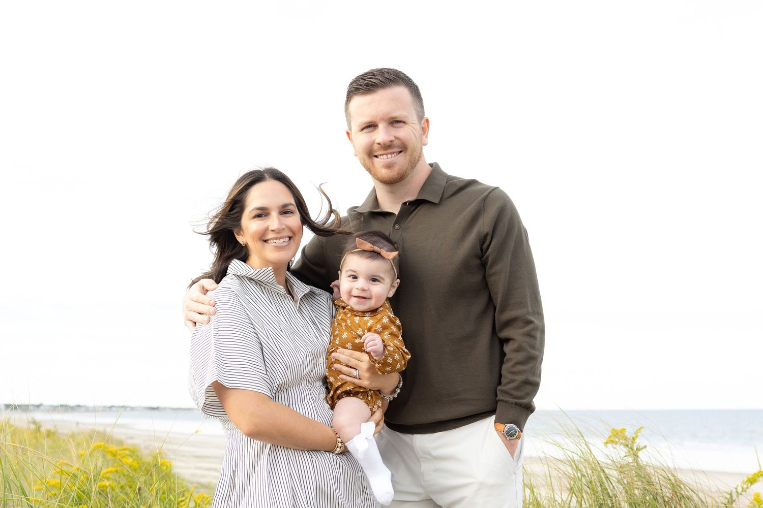 Joyful family portrait session at the beach during golden hour.