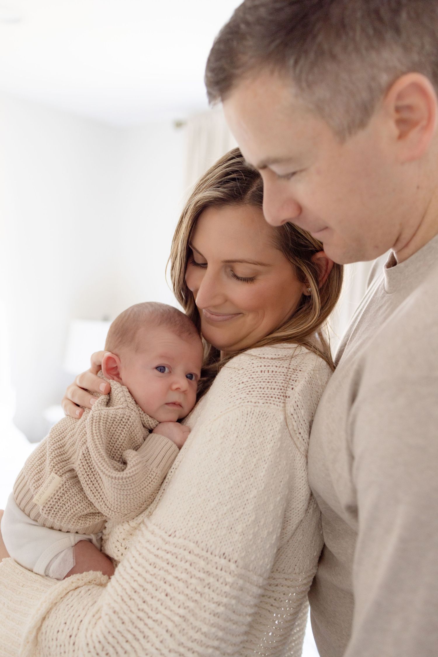 Tender family moment with newborn baby in neutral colored sweaters.