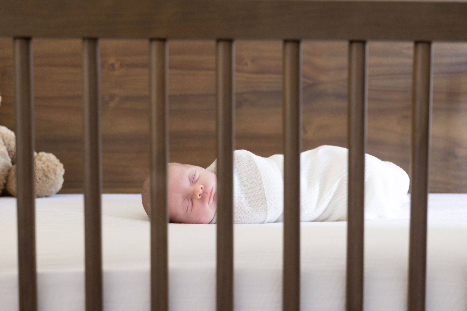 Close-up view of wooden crib bars in a nursery setting.