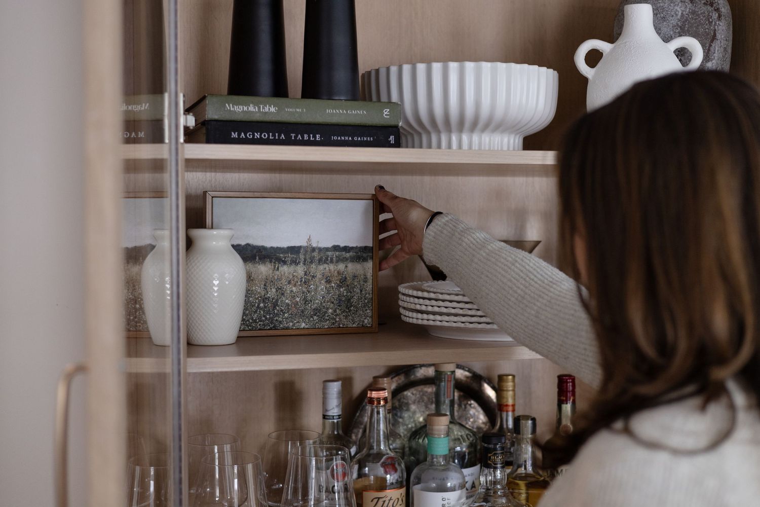 Kitchen shelving displaying white ceramic dishes and cookbooks with decorative accessories.