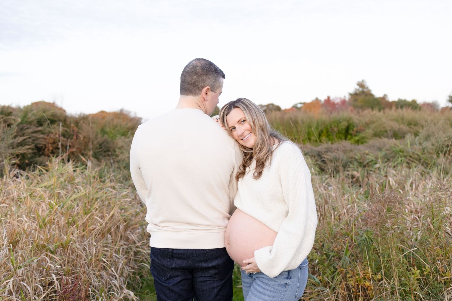Couple embracing in outdoor field during golden hour.