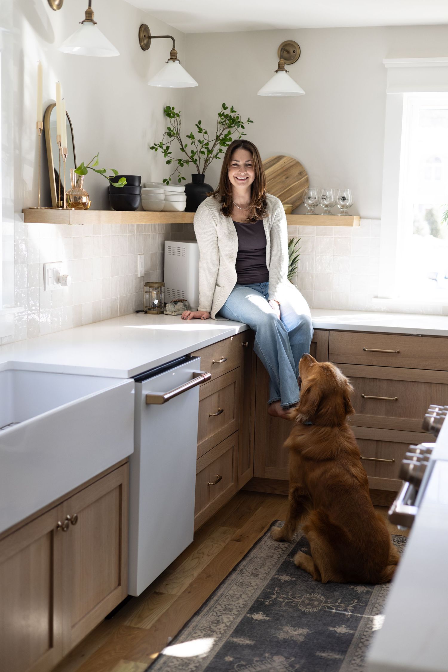 Bright modern kitchen with farmhouse sink, wooden cabinets and golden retriever companion.